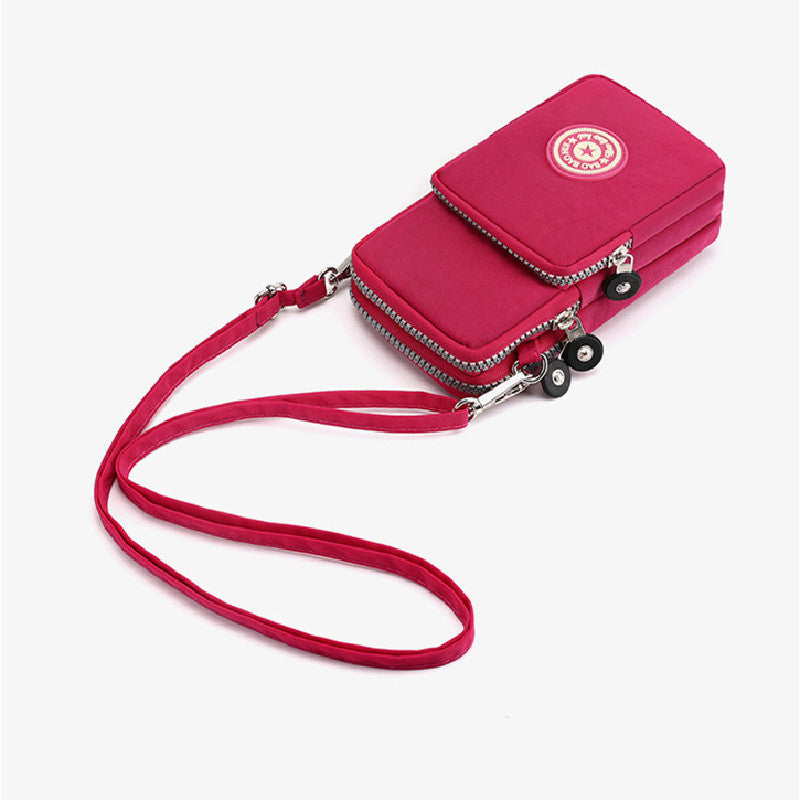 Rote Umhängetasche mit mehreren Reißverschlüssen, verstellbarem Gurt und Markenlogo. Ideal für Damenmode, praktisch und stilvoll.