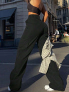 Frau in schwarzer Cargo-Hose und Crop-Top auf städtischer Straße. Modetrend, Streetwear, lässiger Stil, urbane Mode, Sommeroutfit.