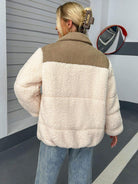 Frau trägt modische Teddyjacke in Cremeweiß, kombiniert mit blauer Jeans. Wintermode, kuscheliger Look, trendige Damenbekleidung.