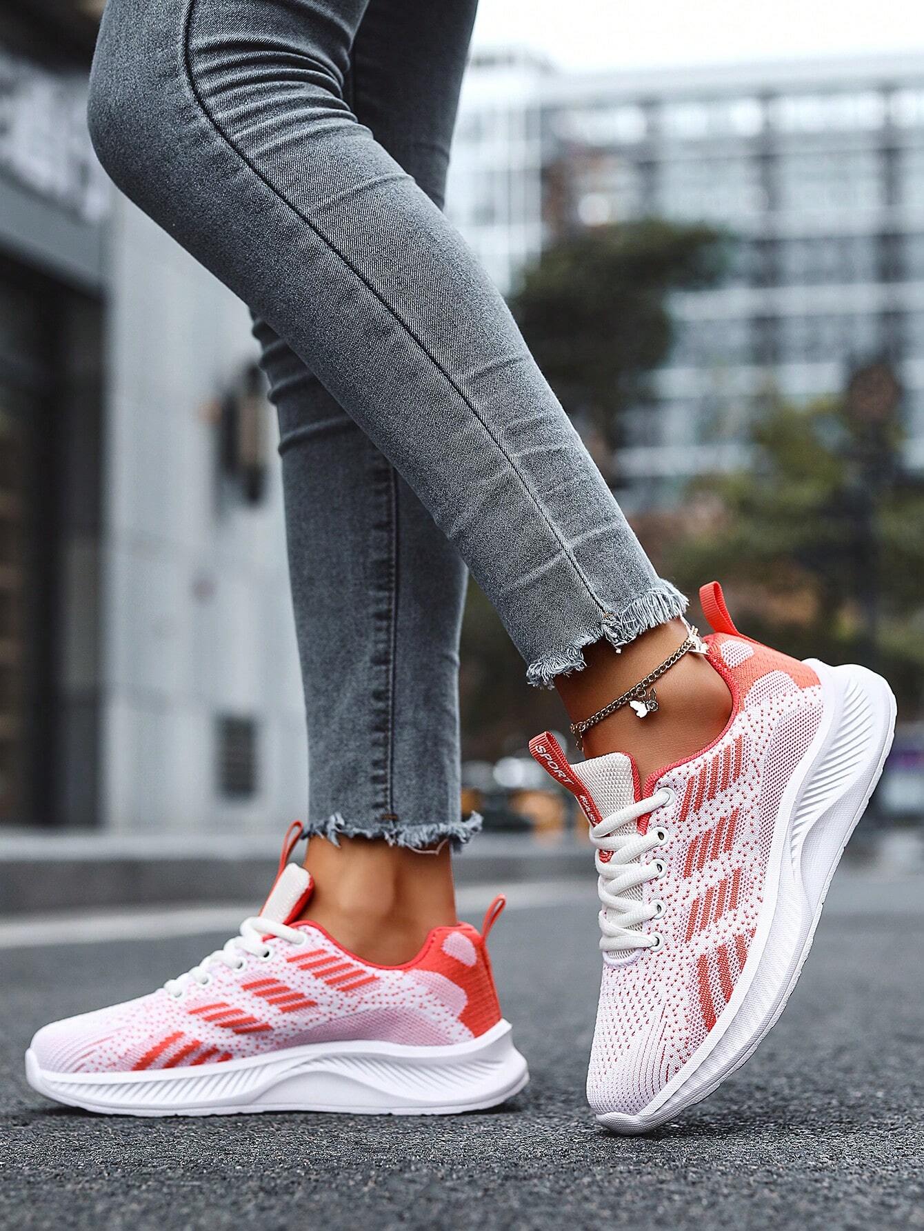 Frau trägt rosa-weiße Sportschuhe, graue Jeans, Straßenhintergrund, modisch, bequem.