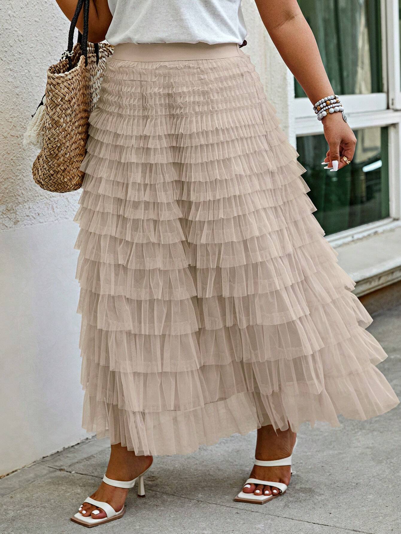 Frau in beiger Tüllrock, Rüschen, Sommermode, mit Strohtasche und weißen Sandalen.
