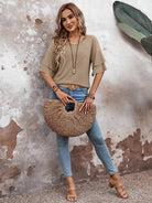 Frau in beiger Bluse und blauer Jeans mit Strohtasche, lässiger Sommerlook, Modefotografie.