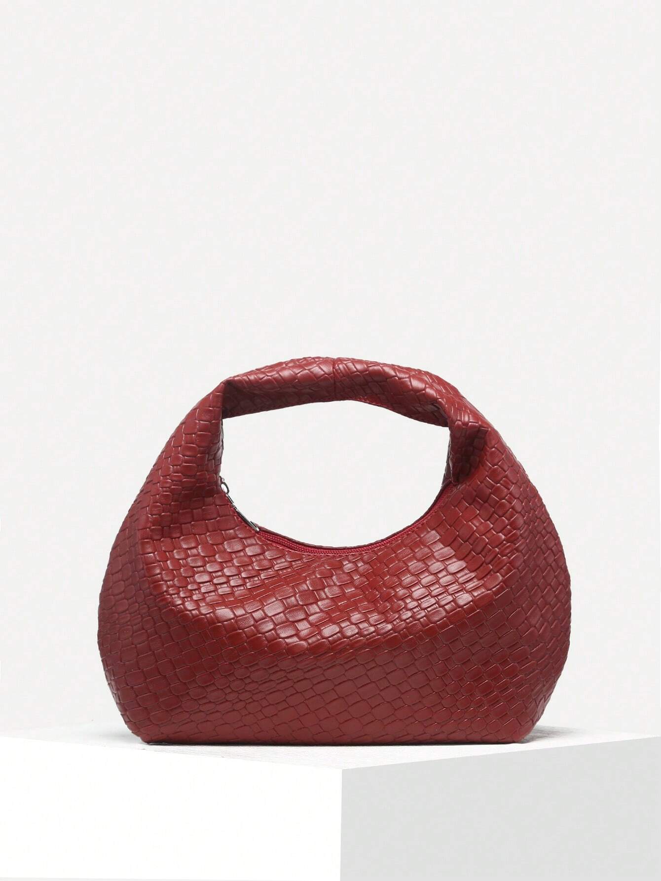 Rote geflochtene Handtasche aus Leder auf weißem Hintergrund, modisches Accessoire.
