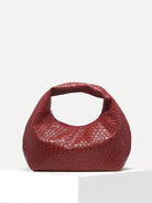 Rote geflochtene Handtasche aus Leder auf weißem Hintergrund, modisches Accessoire.