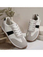 Weiße Sneaker mit grauen Akzenten, schwarzem Streifen, Gummisohle, auf Holzkiste, modern.