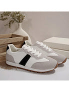 Weiße und graue Sneaker mit schwarzem Streifen, Damenmode, Freizeitschuhe, Holzbox im Hintergrund.