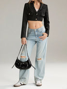 Damenmode: Schwarzes Crop-Blazer-Jacke, kombiniert mit hellblauen, zerrissenen Jeans und schwarzer Handtasche. Trendy Streetwear-Look.