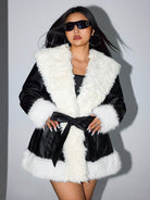 Damenmantel aus Kunstleder mit weißem Kunstfellkragen, modisch und elegant, ideal für Wintermode. Perfekt kombiniert mit Sonnenbrille.