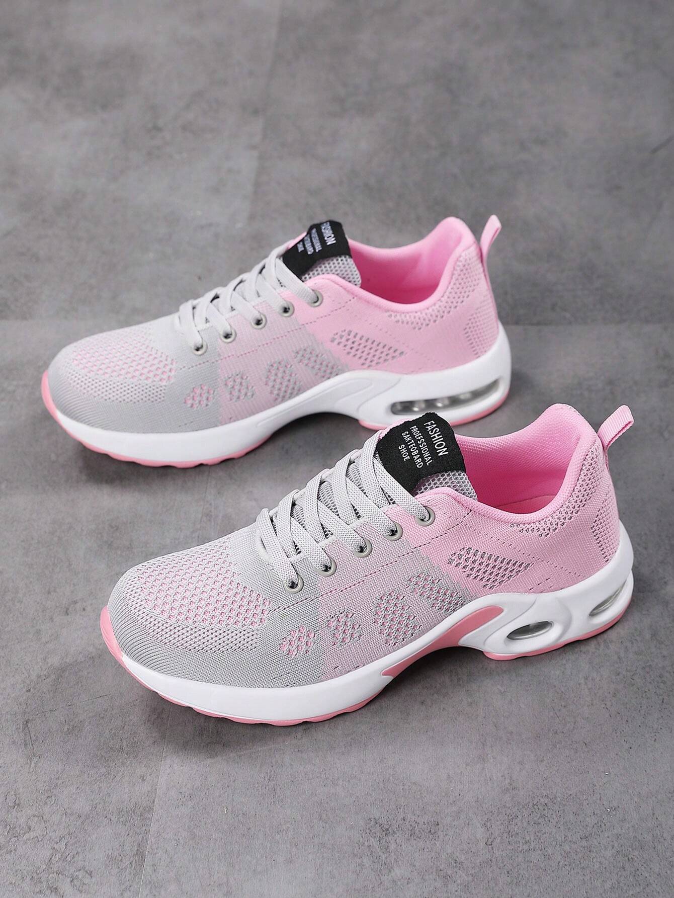 Graue und rosa Damen-Sneaker, atmungsaktiv, Sportschuhe, modisch, auf grauem Hintergrund.