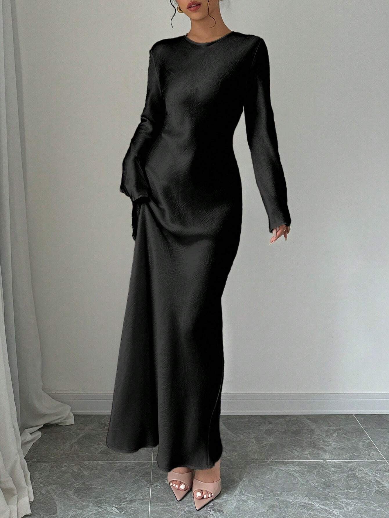 Elegantes schwarzes Maxikleid mit langen Ärmeln, figurbetontem Schnitt und fließendem Stoff. Perfekt für Abendveranstaltungen und formelle Anlässe.