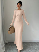 Elegantes langes beiges Kleid, perfekt für Abendveranstaltungen. Figurbetontes Design, kombiniert mit stilvoller Handtasche. Ideal für Modebewusste.