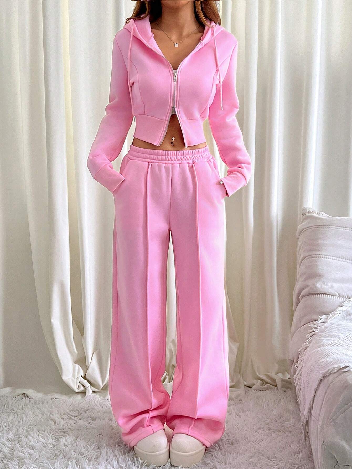 Frau in rosa Jogginganzug, Kapuzenjacke und Hose, gemütliche Damenmode, Wohnzimmer.