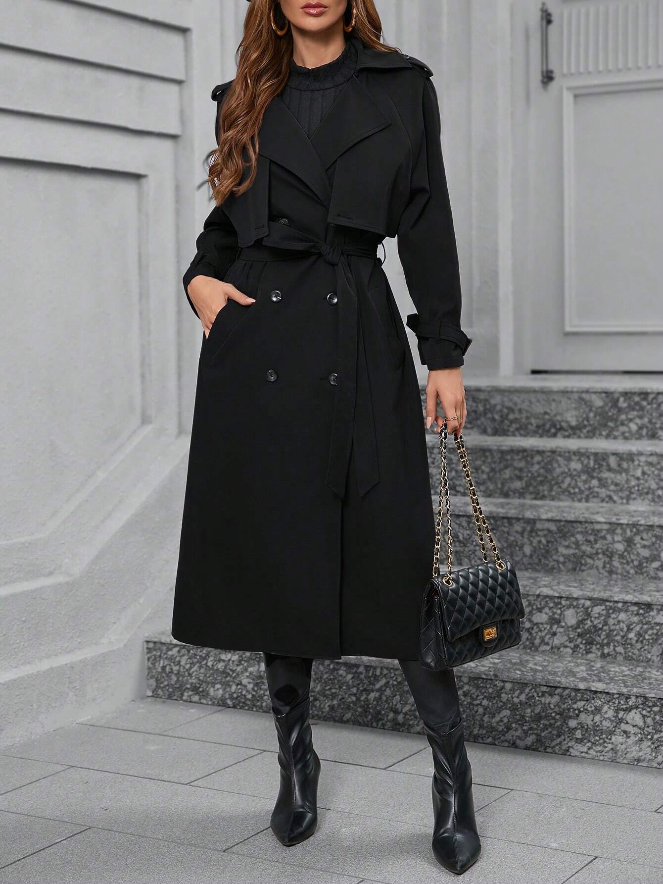 Eleganter schwarzer Trenchcoat für Damen, ideal für Herbstmode. Kombiniert mit Stiefeln und gesteppter Handtasche für stilvollen Look.