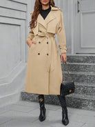 Eleganter beiger Trenchcoat für Damen, ideal für Herbstmode. Stilvoller Mantel mit Gürtel, perfekt kombiniert mit schwarzen Stiefeln und Handtasche.