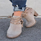 Damenstiefeletten aus Wildleder in Beige mit dekorativen Riemen und Nieten, kombiniert mit hochgekrempelten Jeans. Trendige Herbstmode.