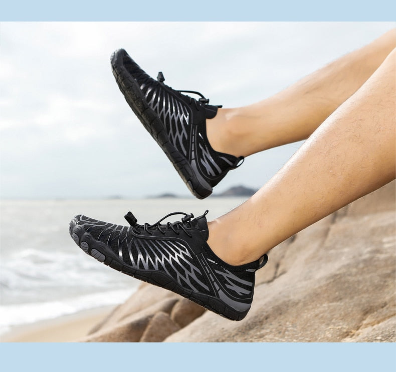 Schwarze Barfußschuhe am Strand, ideal für Outdoor-Aktivitäten. Leicht, atmungsaktiv, rutschfest. Perfekt für Laufen und Wandern.