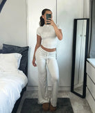Frau in grauem Lounge-Set posiert vor Spiegel, gemütliche Mode, Homewear, bequeme Kleidung, modernes Schlafzimmer, Selfie, Freizeitlook.