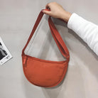 Orange Umhängetasche aus Stoff, halbmondförmig, modisch, handgehalten, minimalistisch.