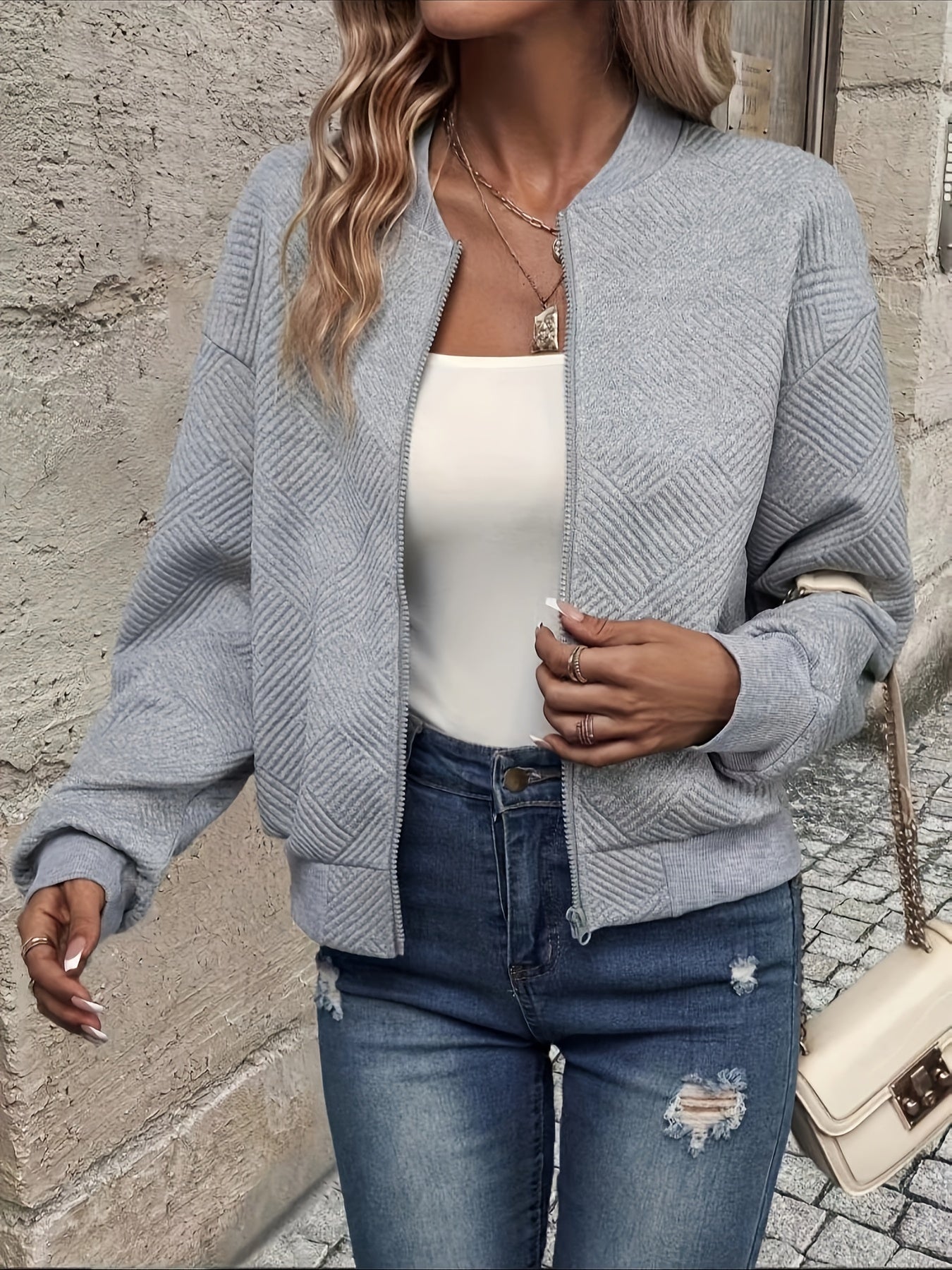 Damenmode: Graue Bomberjacke, weiße Bluse, zerrissene Jeans. Trendige Freizeitkleidung, ideal für Herbst. Streetstyle, lässig, modern.