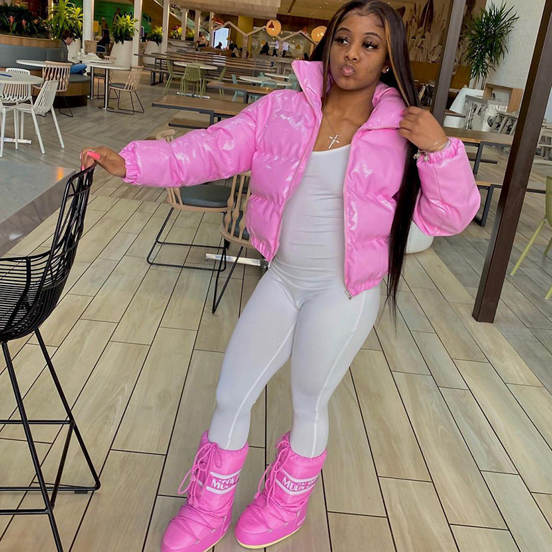 Frau in rosa Daunenjacke und Stiefeln, posiert in modernem Café. Modetrend, Wintermode, stilvolle Outfits, Freizeitkleidung, Damenmode.