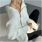 Damenmode: Eleganter weißer Strickpullover mit Reißverschluss, kombiniert mit schwarzen Leggings. Perfekt für stilvolle Herbst- und Winteroutfits.
