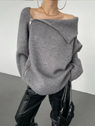 Grauer, asymmetrischer Strickpullover mit Reißverschluss, kombiniert mit schwarzen Lederhosen. Modischer Look für Herbst/Winter.