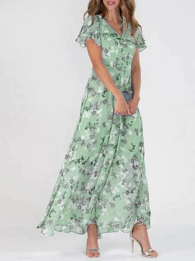 Frau in langem, grünem Blumenkleid, Sommermode, elegante Damenbekleidung, fließender Stoff.
