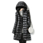Schwarzer Daunenmantel mit Kapuze, stilvoll und warm, ideal für Wintermode. Perfekt kombiniert mit einer eleganten, weißen Umhängetasche.
