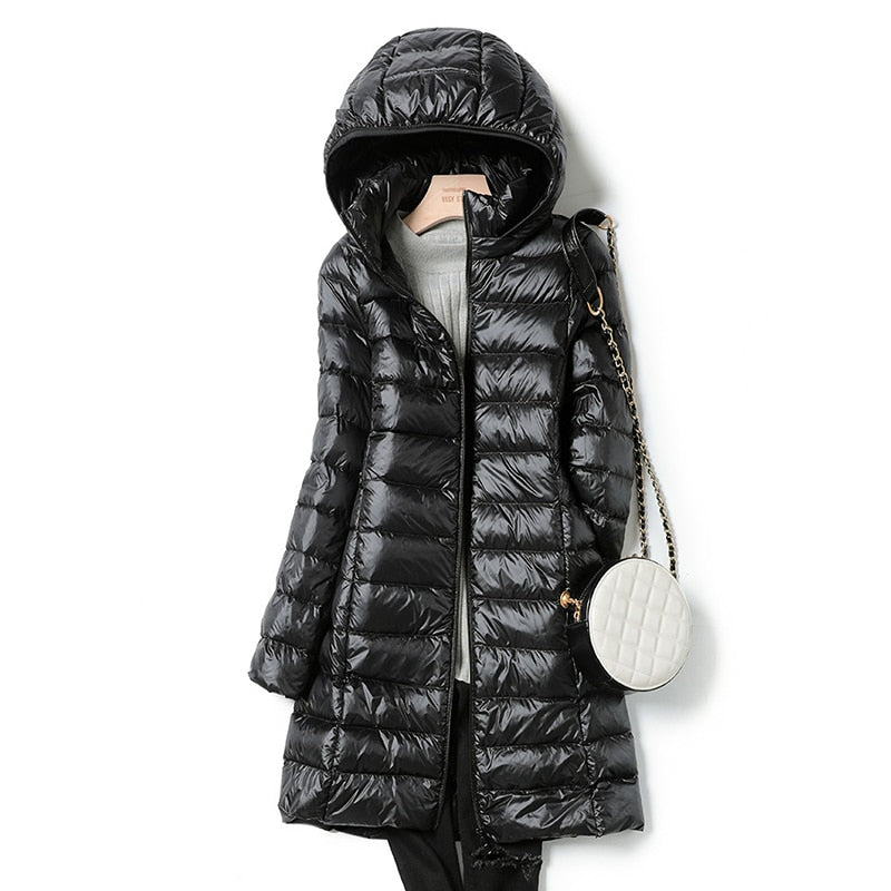 Schwarzer Daunenmantel mit Kapuze, stilvoll und warm, ideal für Wintermode. Perfekt kombiniert mit einer eleganten, weißen Umhängetasche.