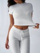 Damen-Sportanzug in Grau, bestehend aus T-Shirt und Jogginghose. Bequem, modisch, ideal für Fitness und Freizeit. Hochwertige Baumwollmischung.