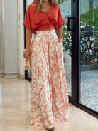 Frau in roter Bluse und weißer, geblümter Hose, Sommermode, elegantes Outfit, Innenraum.