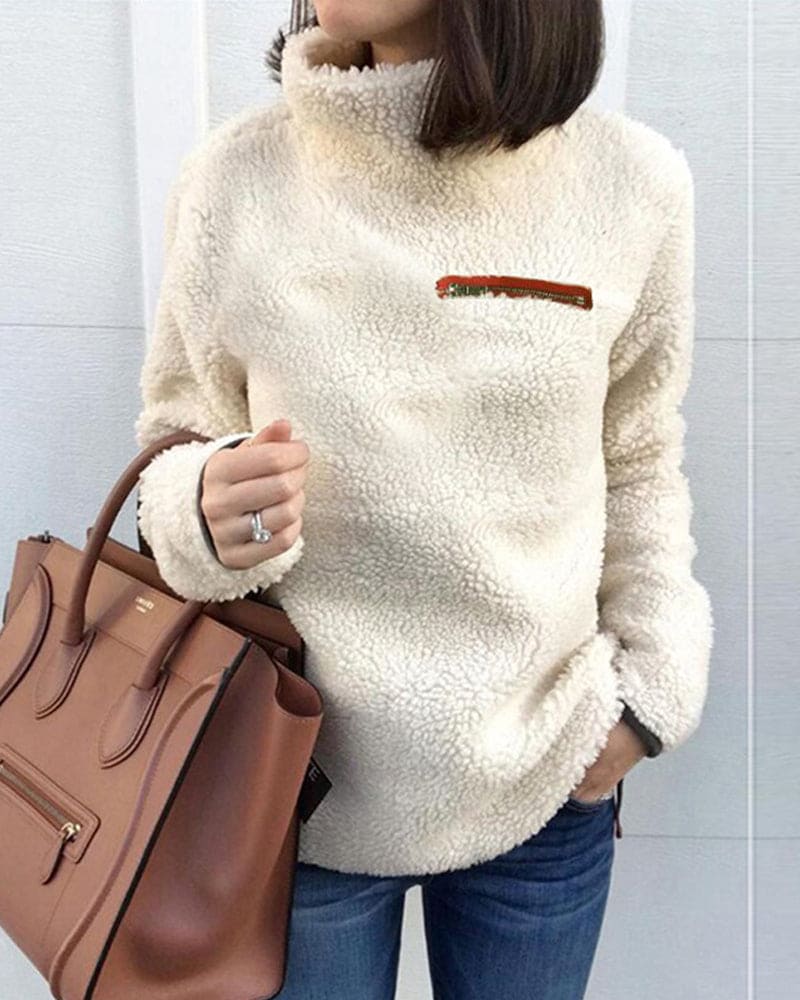 Damen Teddy-Fleece-Pullover in Creme, kuschelig und modisch, kombiniert mit brauner Lederhandtasche. Perfekt für Herbst und Wintermode.