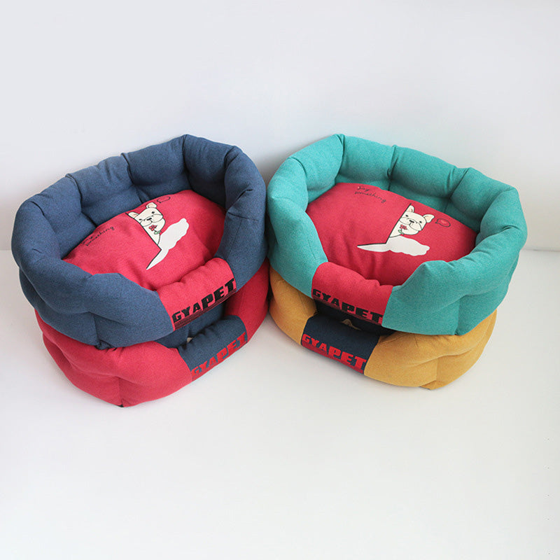 Vier bunte, runde Hundebetten aus Stoff, rot, blau, grün und gelb, mit Katzenmotiv.