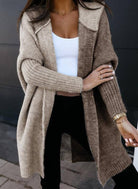 Damen Strickjacke in Beige, offener Schnitt, kombiniert mit weißem Top und schwarzer Hose. Modischer Herbst-Look, ideal für kühle Tage.