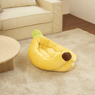 Gelbes Bananen-Split-Haustierbett aus Plüsch auf beigem Teppich neben Sofa und Holztisch.