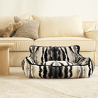 Zebra-Muster Haustiersofa vor beigem Sofa, luxuriöses Design, gemütliches Wohnzimmer.