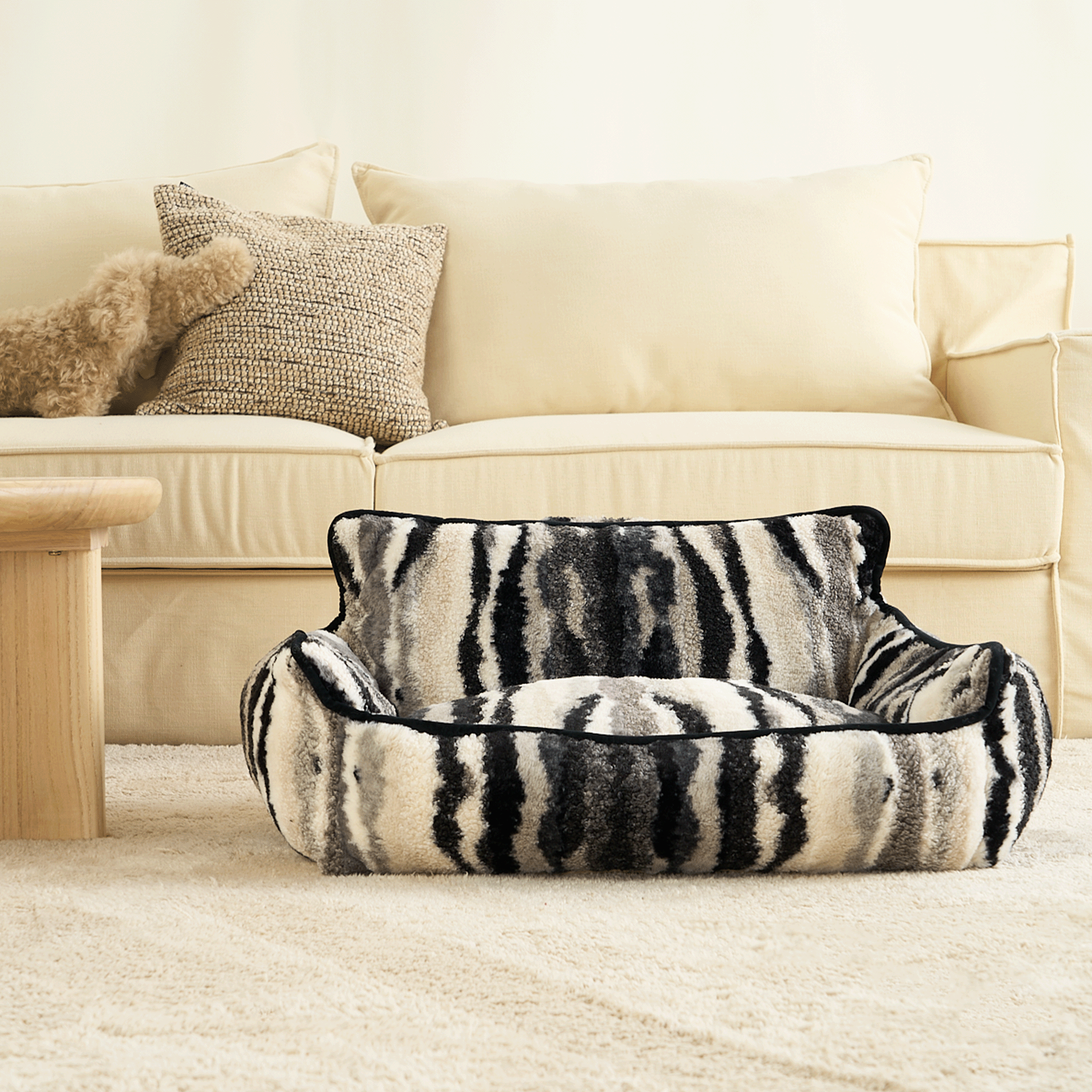 Zebra-Muster Haustiersofa vor beigem Sofa, luxuriöses Design, gemütliches Wohnzimmer.
