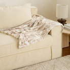 Kuscheldecke aus Kunstfell in Beige auf beigem Sofa, gemütliche Wohnaccessoires, Wohnzimmerdeko.