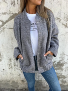 Graue Strickjacke Damenmode, lässig und stilvoll, kombiniert mit weißem T-Shirt und blauer Jeans. Perfekt für Herbst-Outfits und Streetstyle.
