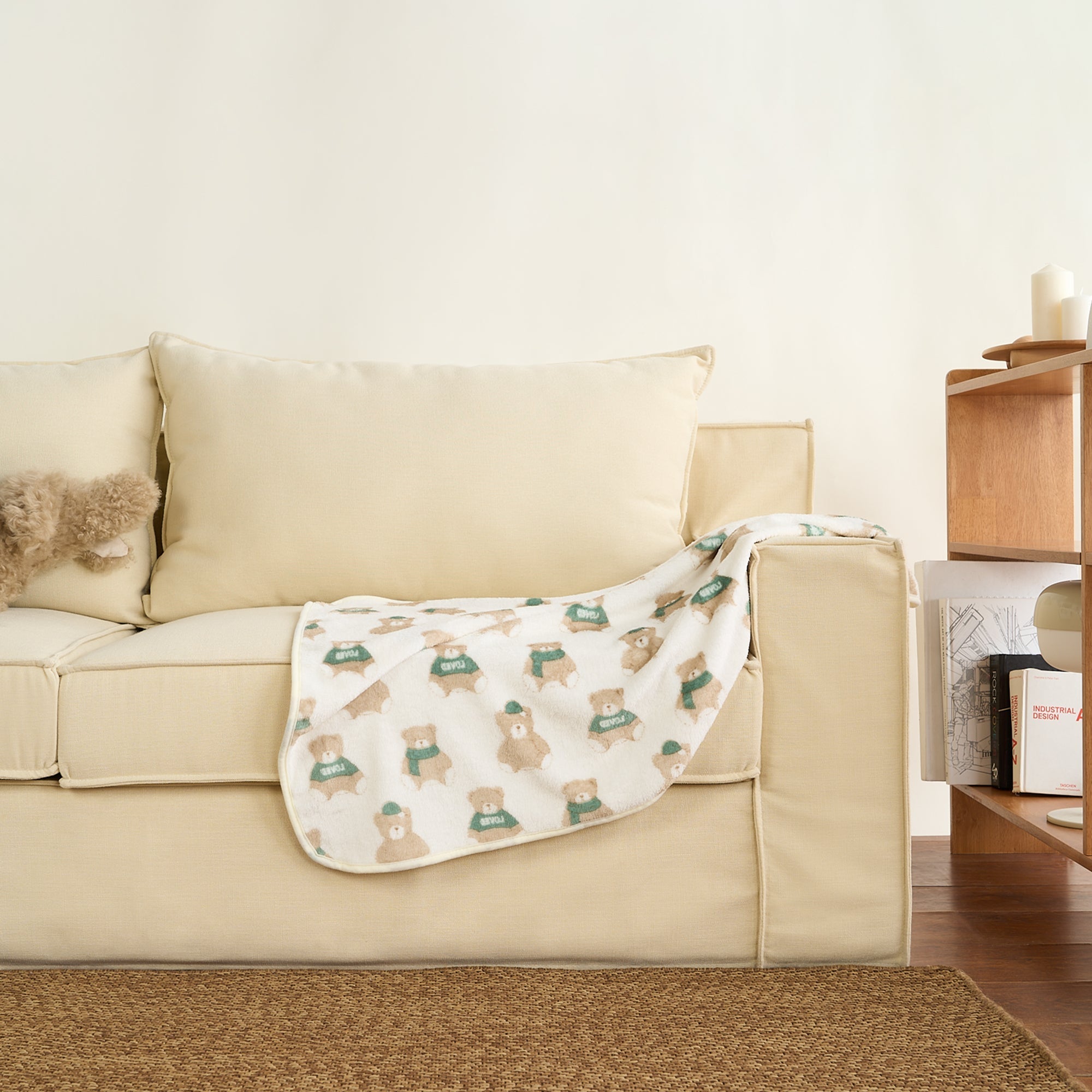 Kuscheldecke für Haustiere auf beigem Sofa, bedruckt mit niedlichen Tiermotiven, Wohnzimmerdekor.