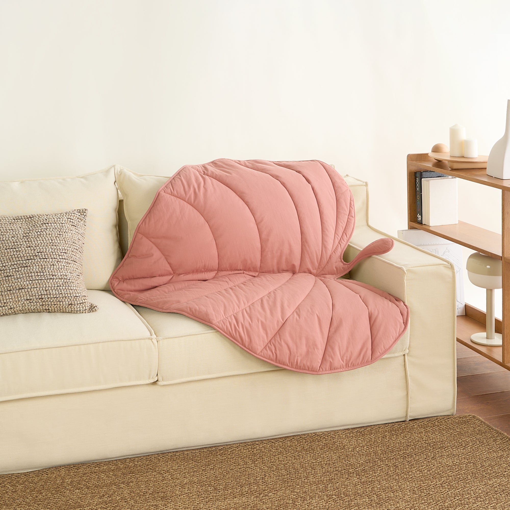 Rosa Blatt-Design Haustierdecke auf cremefarbenem Sofa, gemütlich, stilvoll, Wohnzimmer-Dekor.