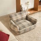 Kariertes Hundebett aus weichem Stoff, beige und blau, auf Teppichboden im Wohnzimmer.