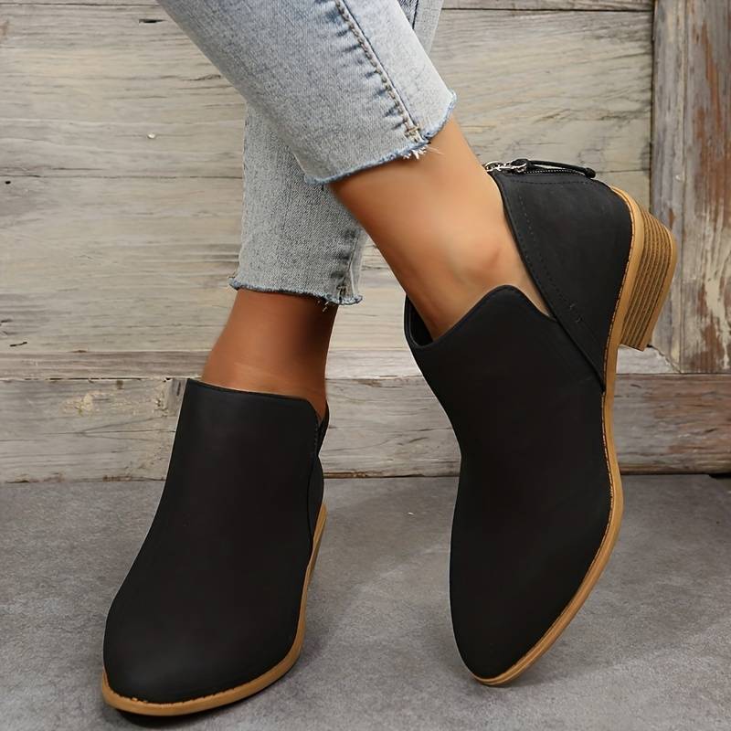 Schwarze Damen-Stiefeletten mit Blockabsatz, kombiniert mit hellblauen Jeans. Modische, bequeme Schuhe für Herbst und Winter.