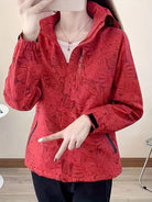 Rote Damenjacke mit floralem Muster, Reißverschluss und Kapuze. Modische Outdoor-Bekleidung, ideal für Herbst und Frühling.