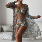 Frau in buntem, gemustertem Strandoutfit mit Kimono, Top und Shorts. Sommermode, Strandkleidung, Boho-Stil, trendige Damenbekleidung.