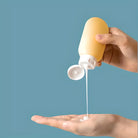 Gelbe Flasche mit Lotion, Hände, Hautpflege, Feuchtigkeitscreme, blaue Hintergrund.