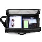 Schwarze Reisetasche mit Sonnenbrille, Wasserflasche, Smartphone und Kleidung, ideal für Reisen.