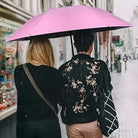 Zwei Personen unter rosa Regenschirm, bestickte Jacke, Stadtstraße, regnerisches Wetter.
