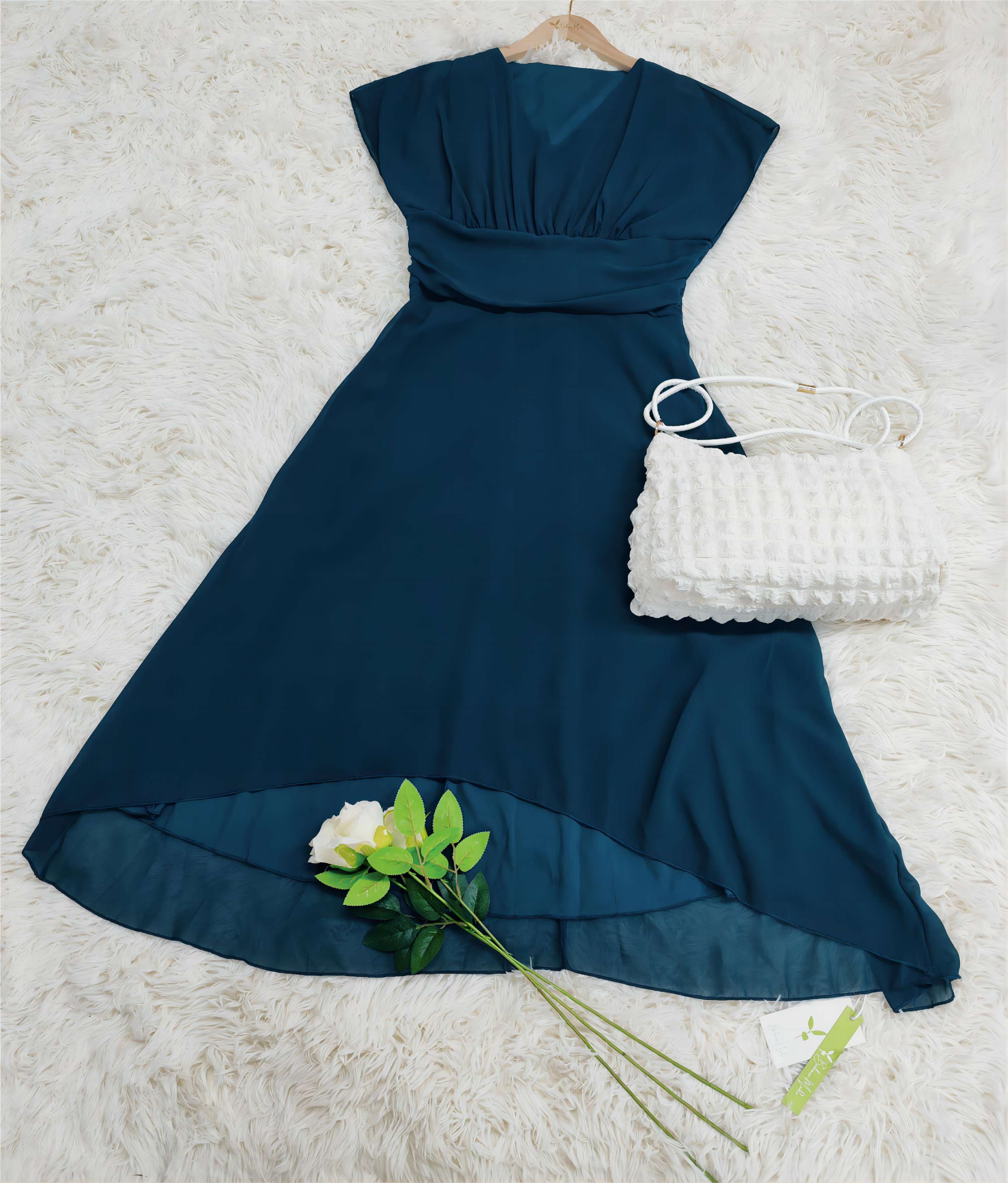 Elegantes blaues Abendkleid aus Chiffon mit V-Ausschnitt, kombiniert mit weißer Handtasche und Rose. Perfekt für festliche Anlässe.