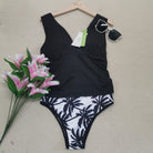 Schwarzer Badeanzug mit Palmenmuster, Sonnenbrille und Blumenstrauß. Perfekt für Strandmode, Sommerurlaub und stilvolle Bademode.